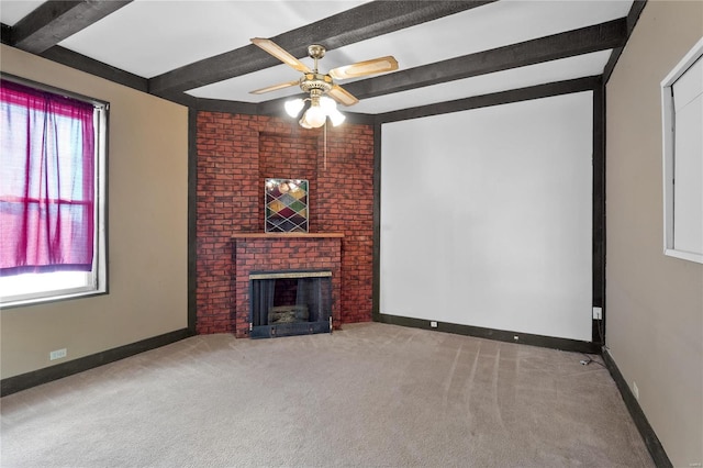 unfurnished living room with ceiling fan, beam ceiling, carpet floors, and a fireplace