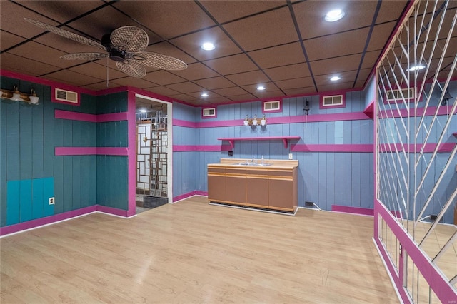 interior space with ceiling fan, hardwood / wood-style floors, wooden walls, and sink