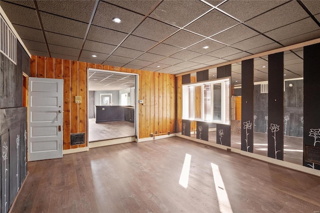 interior space featuring wood-type flooring, a paneled ceiling, and wood walls