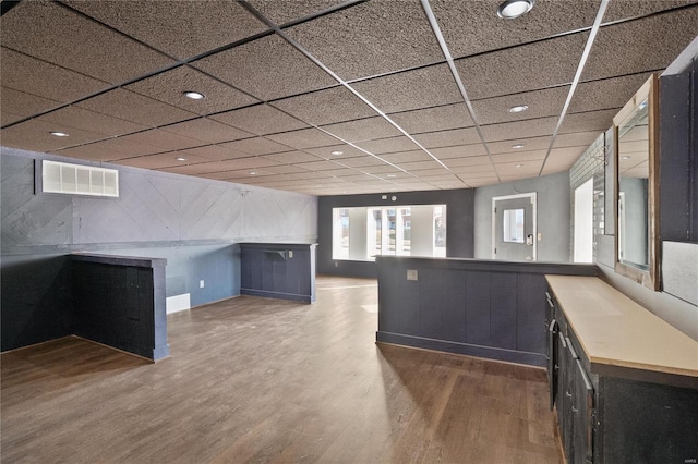 kitchen featuring a drop ceiling, wood-type flooring, and kitchen peninsula