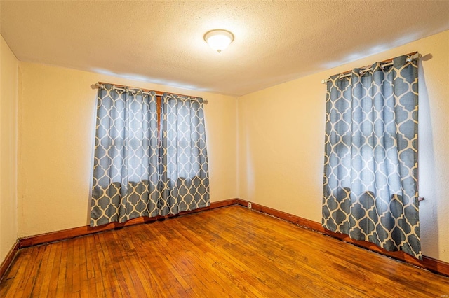 unfurnished room with a textured ceiling and hardwood / wood-style flooring