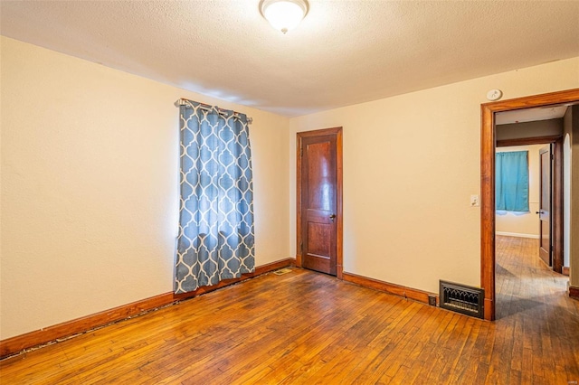 spare room featuring dark hardwood / wood-style flooring and a textured ceiling