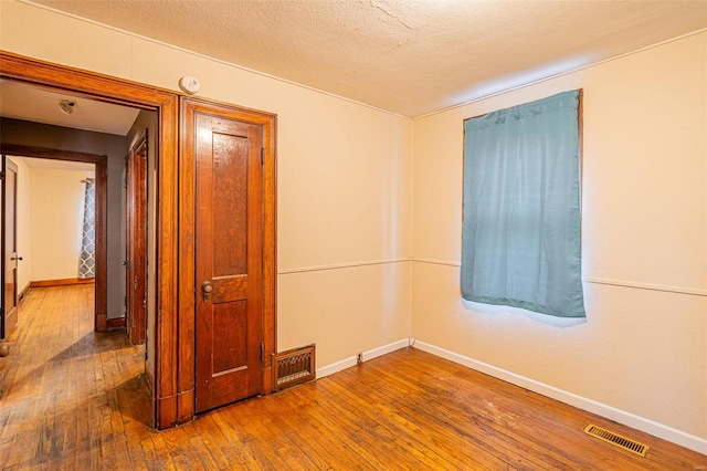 unfurnished room featuring wood-type flooring and a textured ceiling