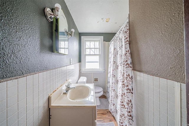 bathroom with toilet, vanity, tile walls, and hardwood / wood-style flooring