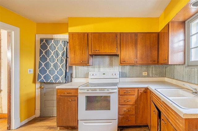 kitchen featuring white electric range, light hardwood / wood-style floors, tasteful backsplash, and sink