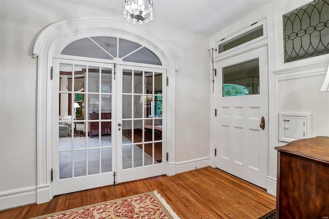 entryway with wood-type flooring and a chandelier