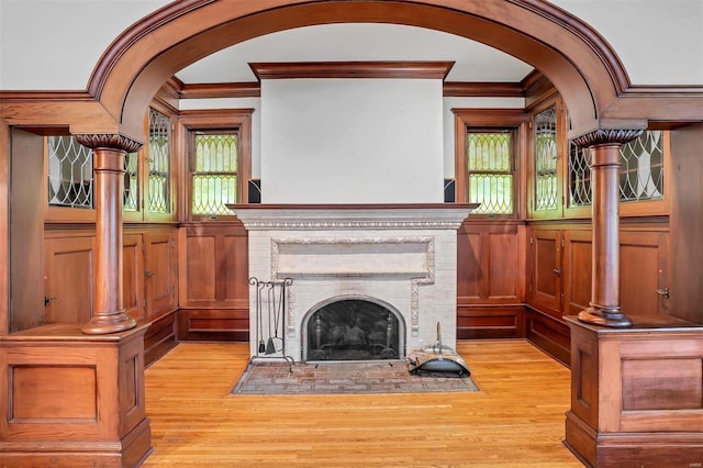 unfurnished living room featuring light wood-type flooring, a brick fireplace, and crown molding