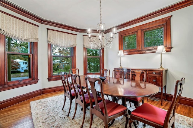 dining area featuring a notable chandelier, ornamental molding, and light hardwood / wood-style flooring