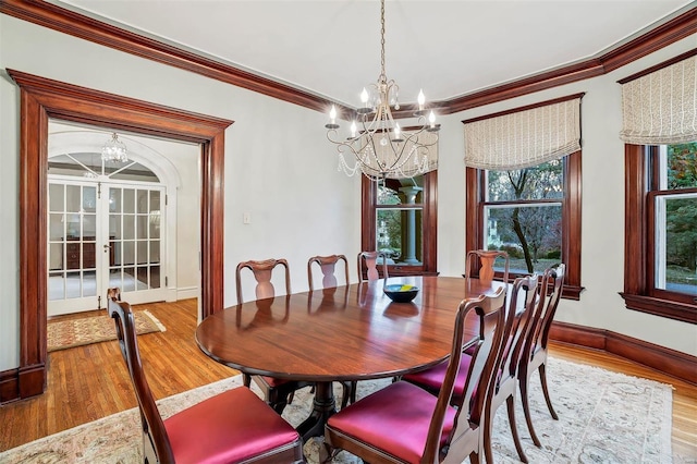 dining space with a chandelier, wood-type flooring, french doors, and crown molding