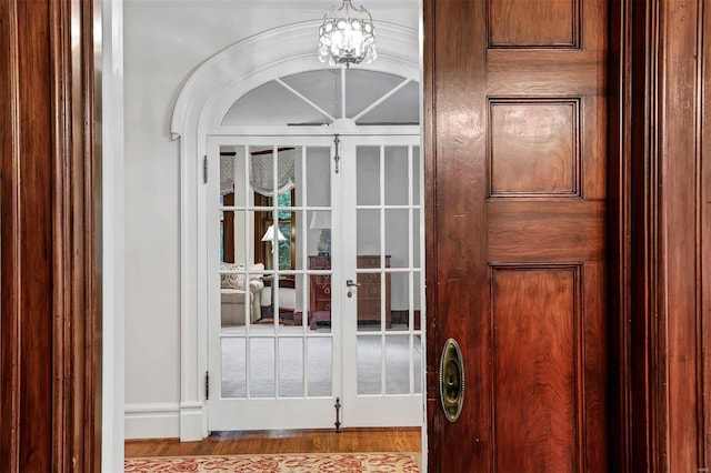 doorway with french doors, light hardwood / wood-style floors, and an inviting chandelier