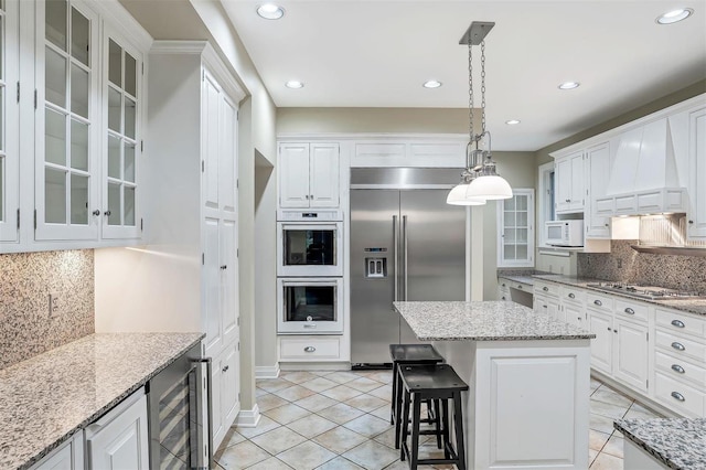 kitchen featuring hanging light fixtures, white cabinets, beverage cooler, and appliances with stainless steel finishes