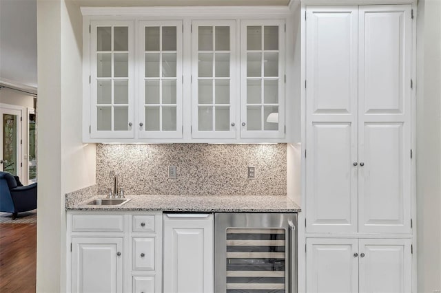 bar featuring white cabinetry, sink, beverage cooler, light stone counters, and hardwood / wood-style floors