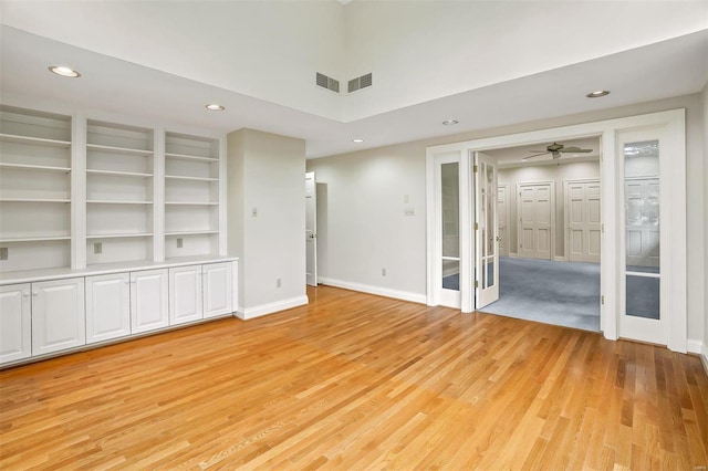 unfurnished living room with ceiling fan, built in features, and light wood-type flooring