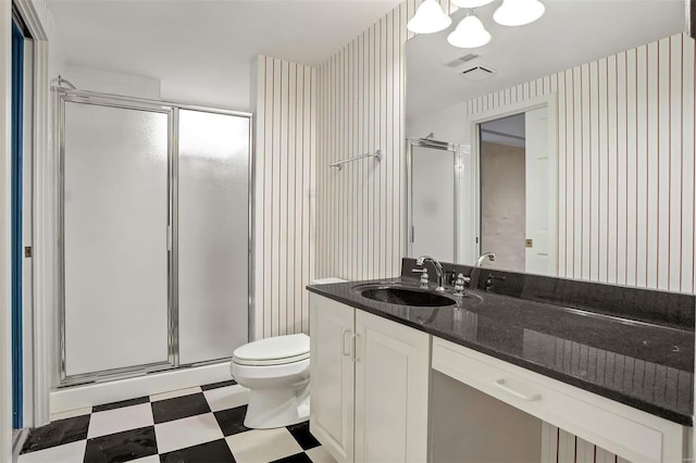 bathroom featuring vanity, a shower with shower door, and toilet