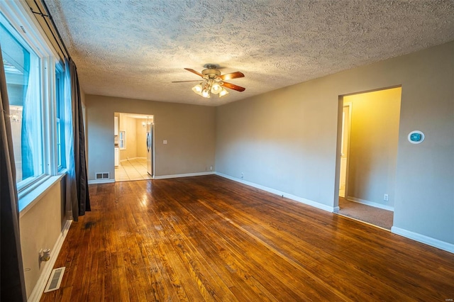 empty room featuring ceiling fan, hardwood / wood-style floors, and a textured ceiling