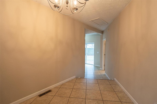 corridor featuring light tile patterned floors, a textured ceiling, and a notable chandelier