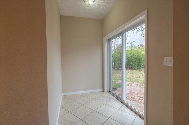 doorway to outside with light tile patterned flooring and a textured ceiling