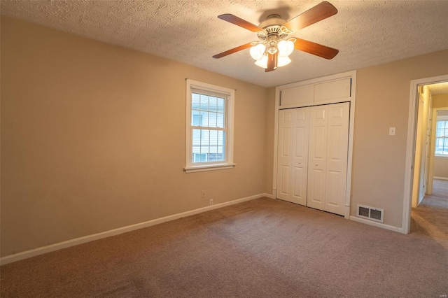 unfurnished bedroom featuring carpet flooring, ceiling fan, a closet, and a textured ceiling