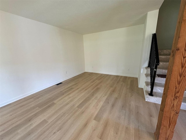 empty room featuring a textured ceiling and light hardwood / wood-style flooring