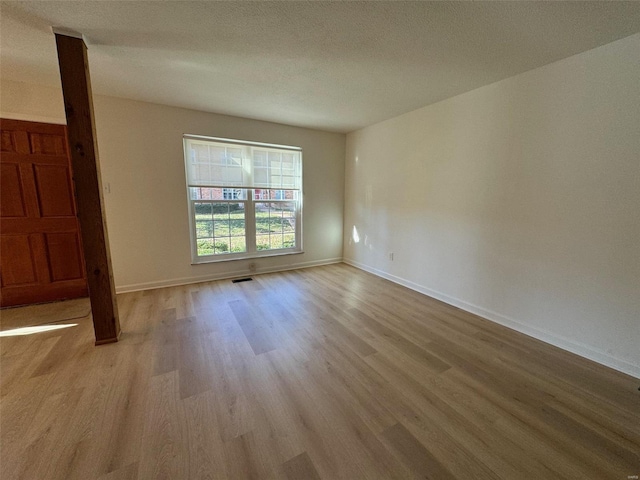 spare room featuring light hardwood / wood-style flooring and a textured ceiling