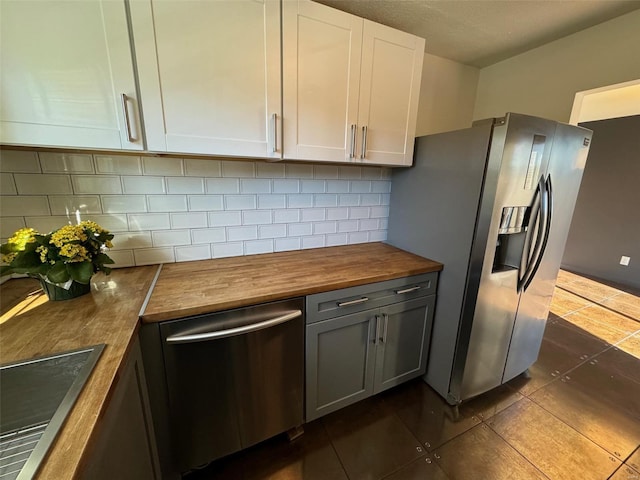 kitchen with stainless steel appliances, white cabinetry, tasteful backsplash, and wooden counters