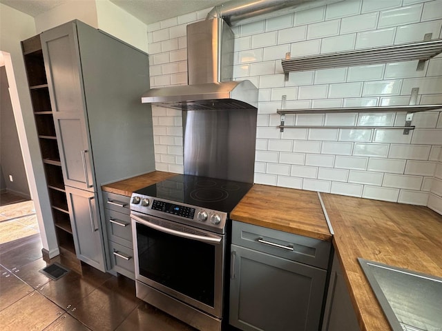 kitchen featuring decorative backsplash, stainless steel electric range, wooden counters, and wall chimney range hood