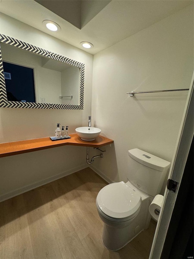 bathroom with hardwood / wood-style flooring, toilet, and sink