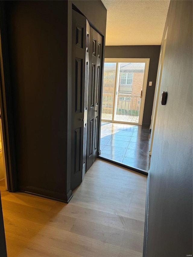 corridor with light hardwood / wood-style floors and a textured ceiling