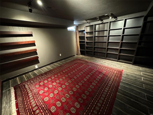 basement with wood-type flooring, a textured ceiling, and track lighting