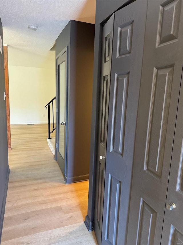 corridor featuring a textured ceiling and light wood-type flooring