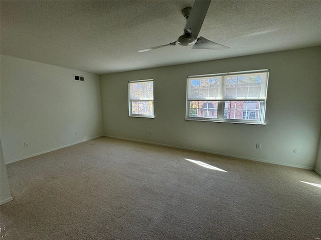 spare room with ceiling fan, light colored carpet, and a textured ceiling