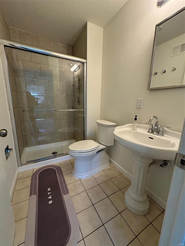 bathroom featuring tile patterned flooring, a shower with door, a textured ceiling, and toilet