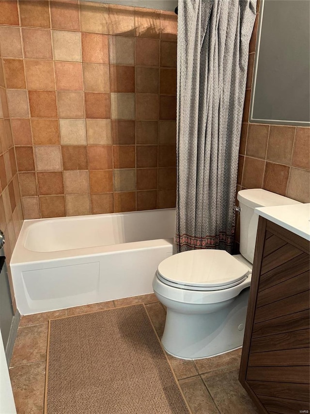 full bathroom featuring shower / bathtub combination with curtain, tile patterned floors, toilet, vanity, and tile walls