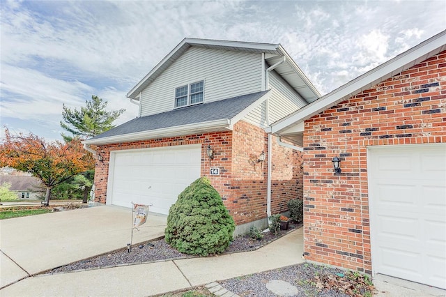 view of property exterior featuring a garage, driveway, brick siding, and roof with shingles