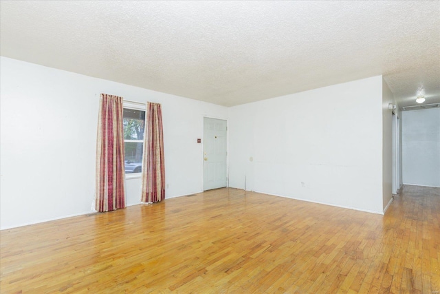 spare room featuring light hardwood / wood-style flooring and a textured ceiling