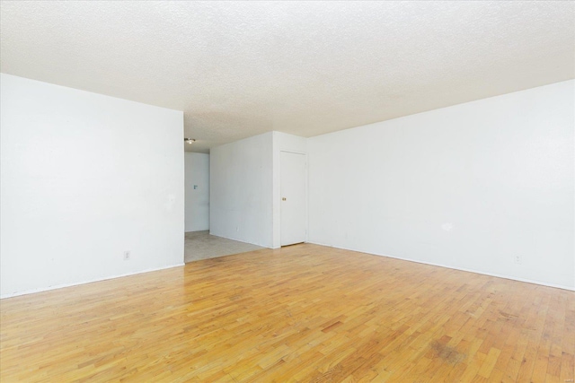 spare room featuring a textured ceiling and light hardwood / wood-style flooring