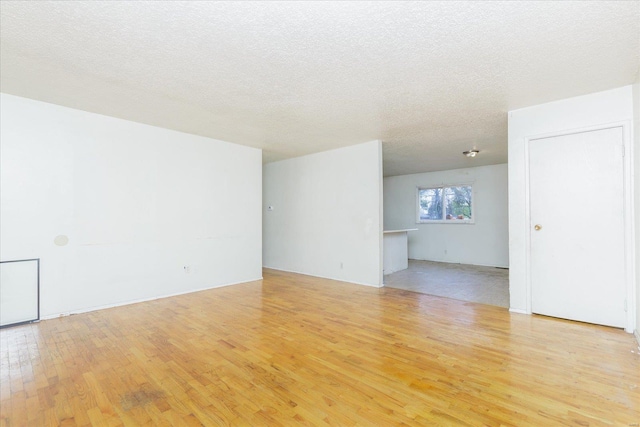 unfurnished room with light hardwood / wood-style floors and a textured ceiling