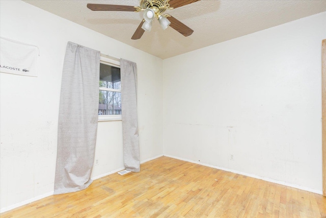 empty room featuring ceiling fan, light wood-type flooring, and a textured ceiling