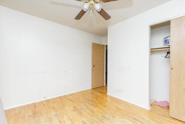 unfurnished bedroom with wood-type flooring, a textured ceiling, a closet, and ceiling fan