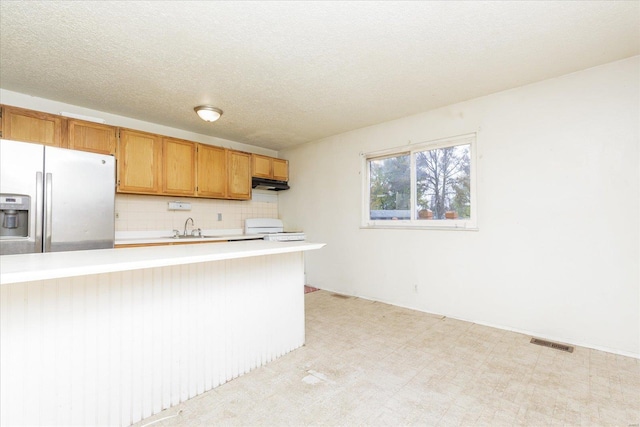 kitchen with kitchen peninsula, backsplash, white range oven, sink, and stainless steel fridge with ice dispenser