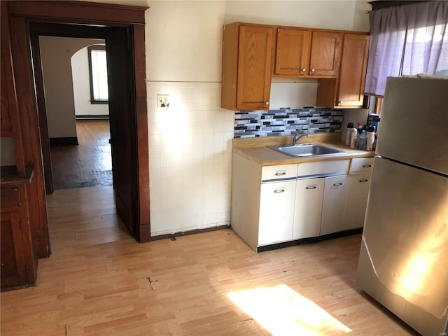 kitchen with stainless steel refrigerator, sink, and light wood-type flooring