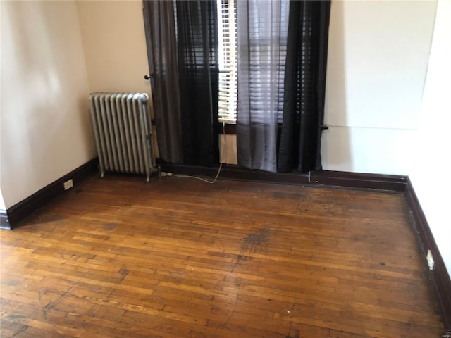 unfurnished room with dark hardwood / wood-style flooring and radiator heating unit