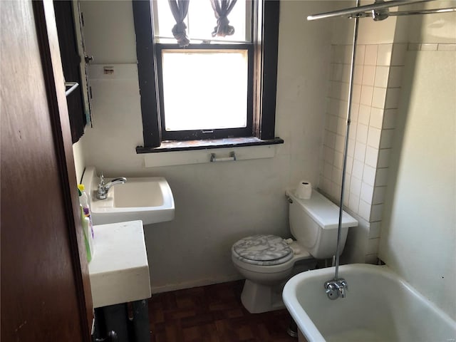 bathroom with a tub to relax in, sink, parquet floors, and toilet