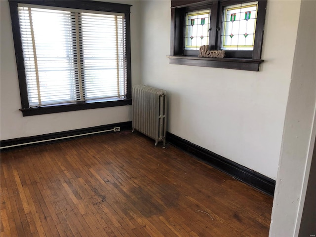 unfurnished room featuring radiator heating unit and dark wood-type flooring