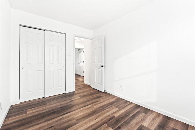 unfurnished bedroom with dark hardwood / wood-style flooring and a closet