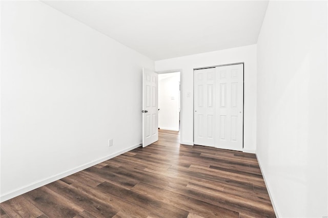 unfurnished bedroom with dark hardwood / wood-style floors and a closet