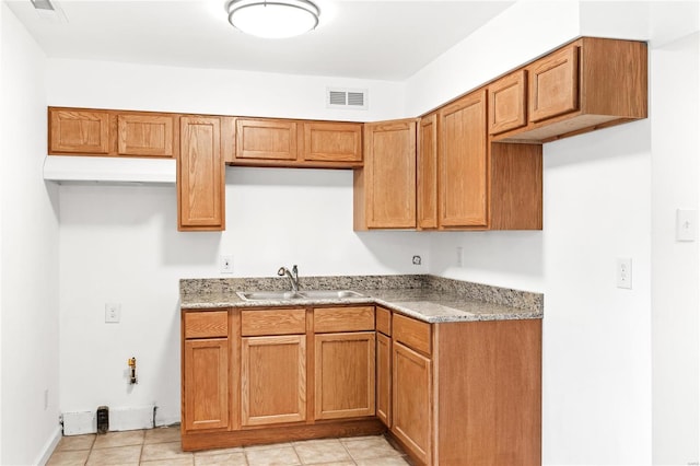 kitchen featuring light stone counters, light tile patterned floors, and sink