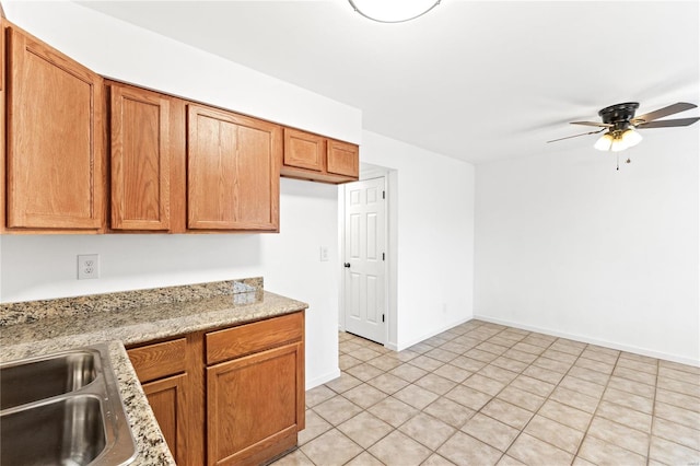 kitchen featuring ceiling fan, light stone countertops, and light tile patterned floors