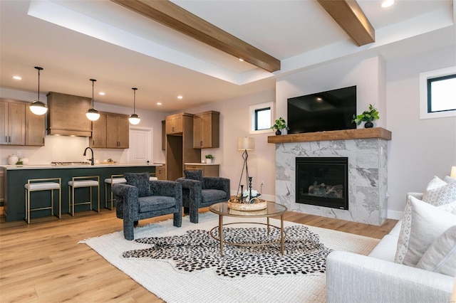 living room with beam ceiling, plenty of natural light, a fireplace, and light hardwood / wood-style floors