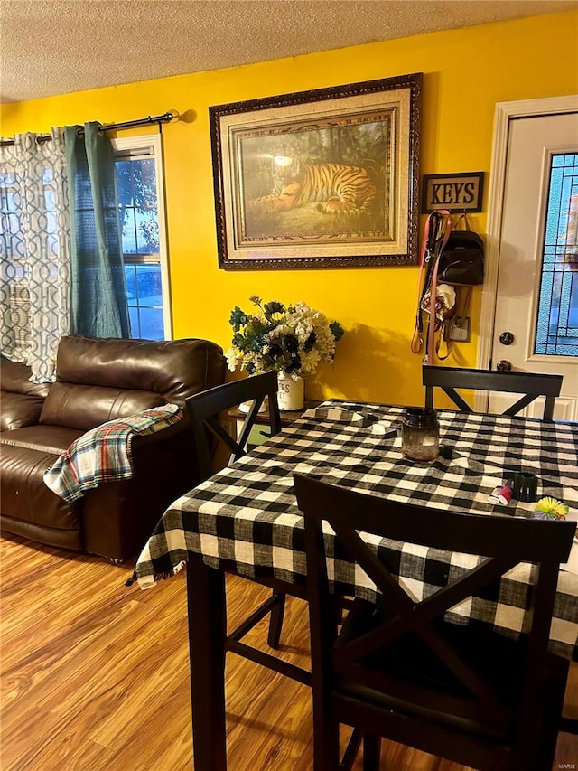 dining space with hardwood / wood-style flooring and a textured ceiling